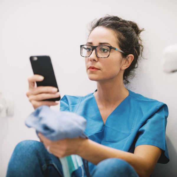 Female doctor in scrubs glasses using social media